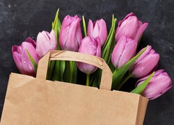 Mokre rozkwitające różowe tulipany w papierowej torbie